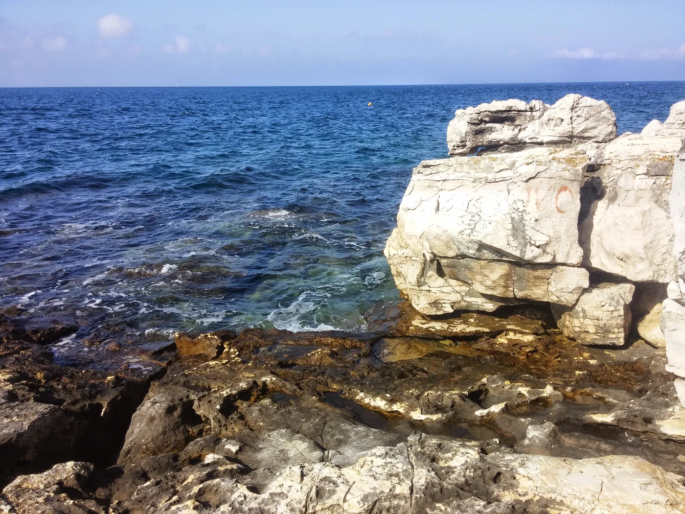 Weißer Kalkfelsen und klares Wasser an der Küste bei Poreč